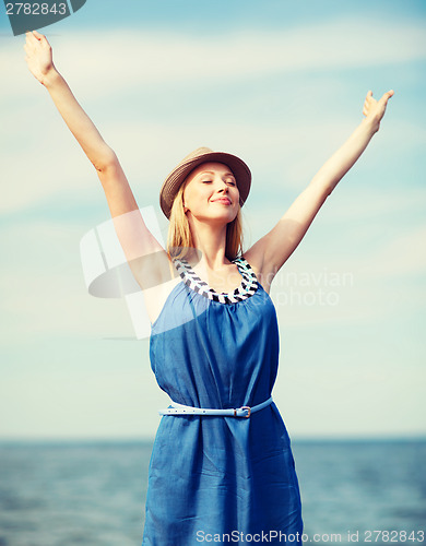 Image of girl with hands up on the beach
