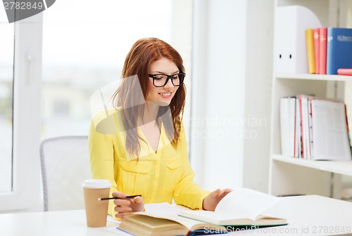 Image of smiling student girl reading books in library