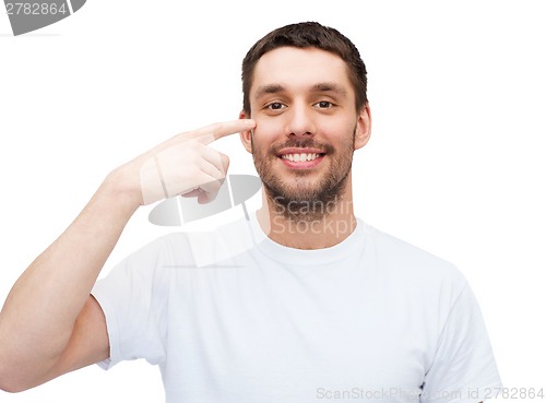 Image of smiling young handsome man pointing to eyes