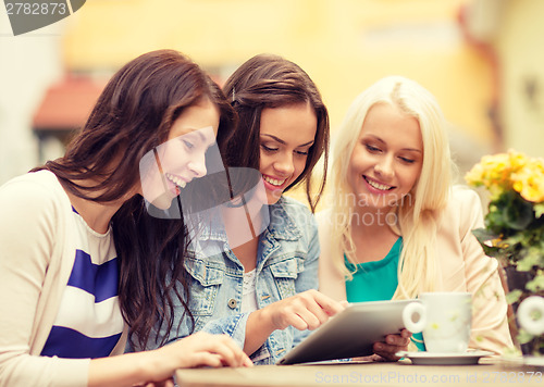 Image of three beautiful girls looking at tablet pc in cafe