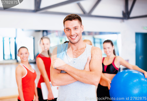 Image of smiling man standing in front of the group in gym
