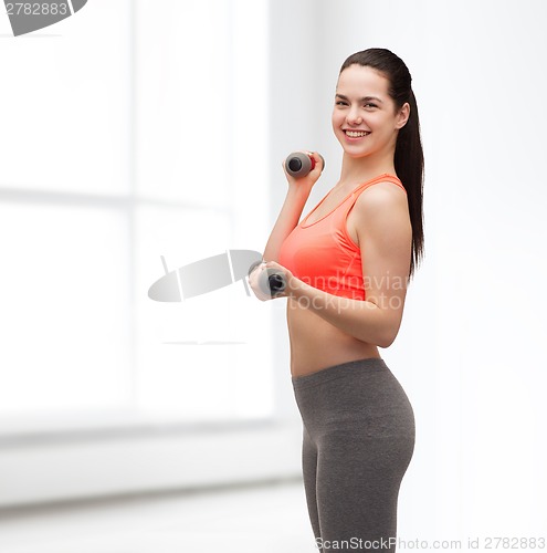 Image of young sporty woman with light dumbbells
