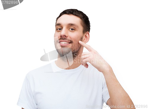 Image of smiling young handsome man pointing to cheek