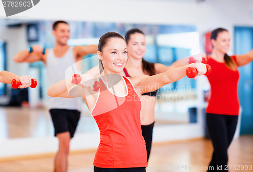 Image of group of smiling people working out with dumbbells