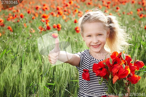 Image of Happy little girl on poppy meadow giving thumb up