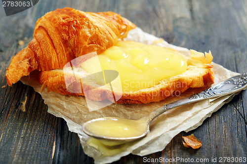 Image of Croissant with cream and teaspoon.