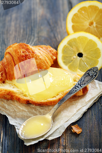 Image of Lemon curd and teaspoon on a slice of fresh croissant.  