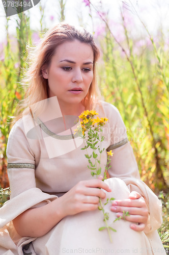 Image of Beautiful sad girl sitting on meadow