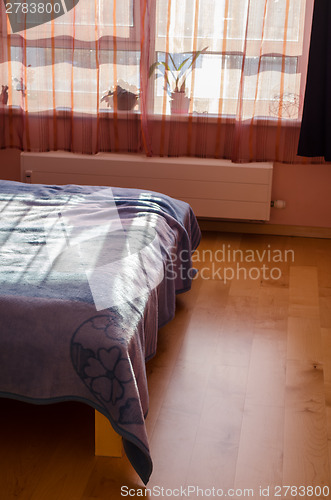 Image of sun shade reflected through curtains on bedspreads 