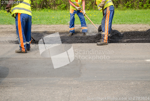 Image of teamworker smoothing asphalt pavement new road  