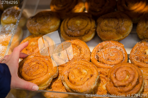 Image of hand hold yeast bun with cinnamon in store 