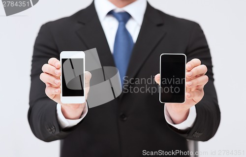 Image of businessman showing smartphones with blank screens