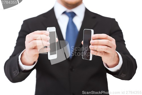 Image of businessman showing smartphones with blank screens