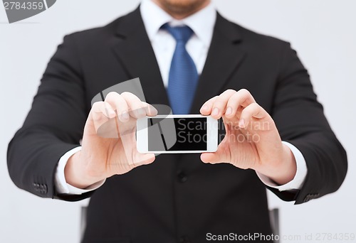 Image of businessman showing smartphone with blank screen