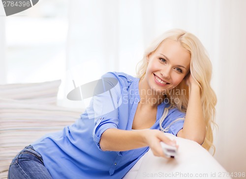 Image of smiling young girl with tv remote control at home