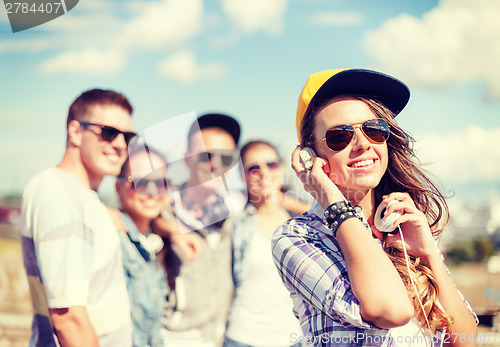 Image of teenage girl with headphones and friends outside
