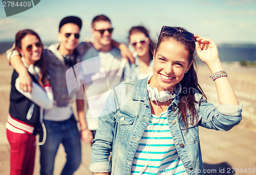 Image of teenage girl with headphones and friends outside