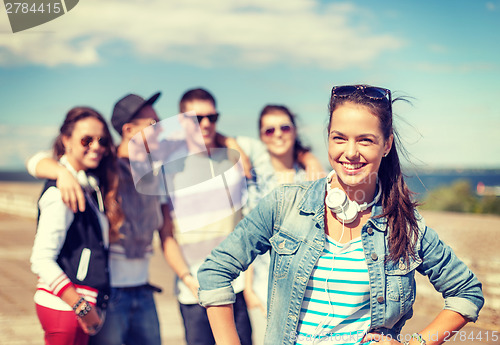 Image of teenage girl with headphones and friends outside