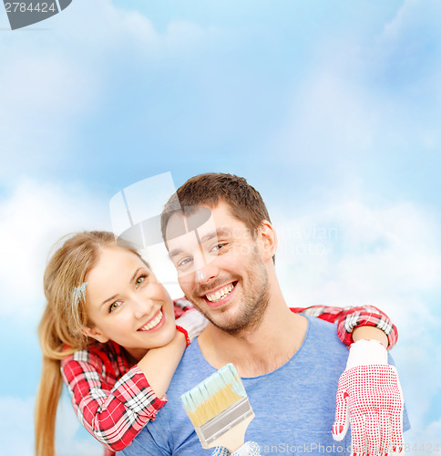 Image of smiling couple covered with paint with paint brush