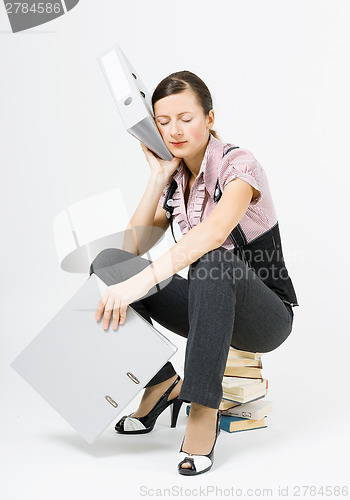 Image of tired woman sleeps sitting on books