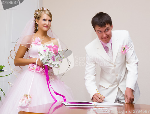 Image of wedding. The groom signs the registration documents