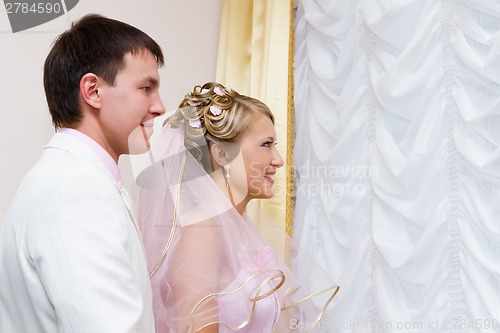 Image of wedding. The bride and groom look out the window