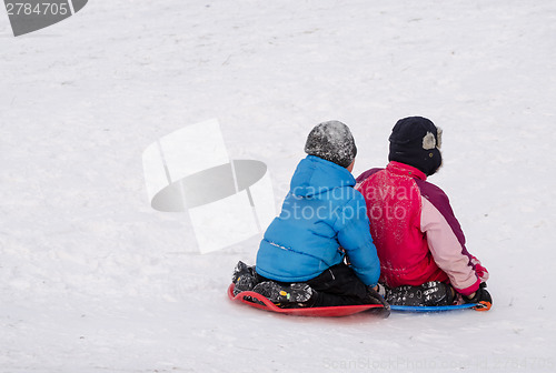 Image of boys slide holding on plastic sled down hill 