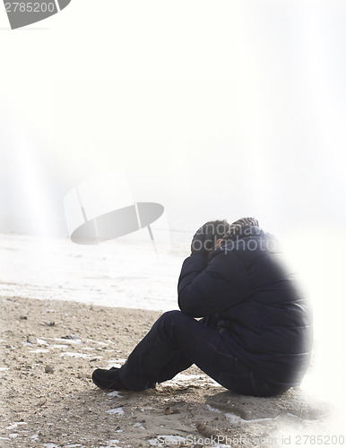 Image of Lonely man sitting on sand