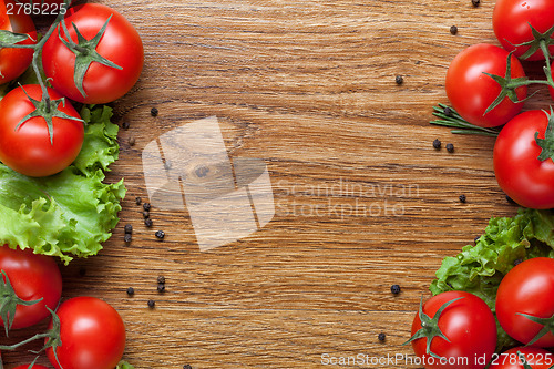Image of red tomatoes with green salad on wood