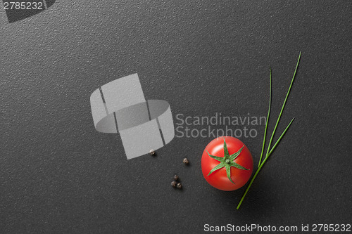 Image of red tomato with green onion on black