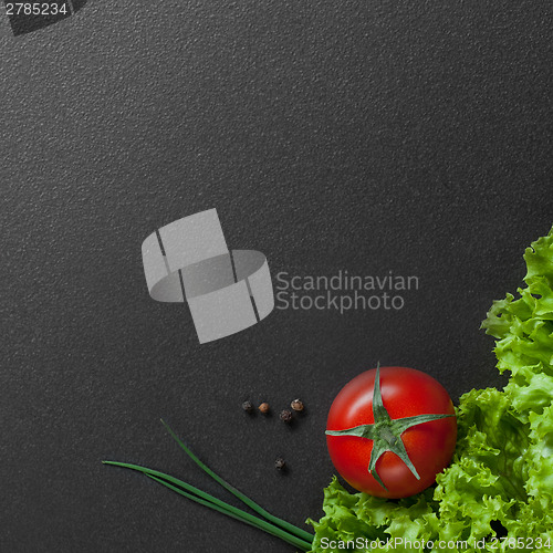 Image of red tomato with green salad on black