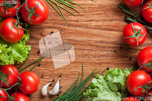 Image of red tomatoes with green salad on wood