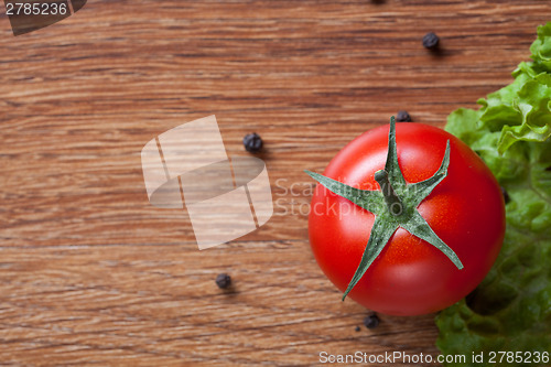 Image of red tomato with green salad on wood