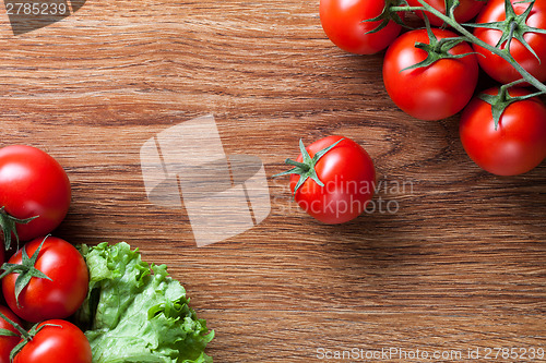 Image of red tomatoes with green salad on wood