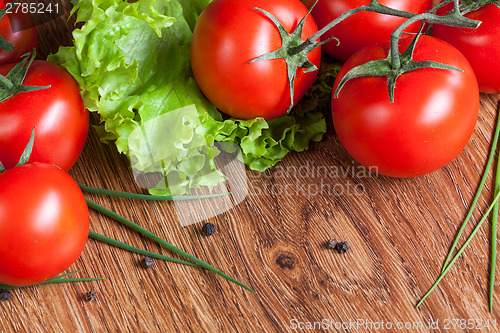 Image of red tomatoes with green salad on wood