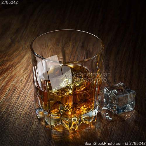 Image of Whiskey with ice in glass on the wood