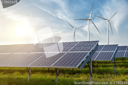 Image of solar panels and wind generators under blue sky on sunset