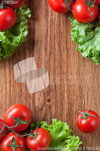 Image of red tomatoes with green salad on wood