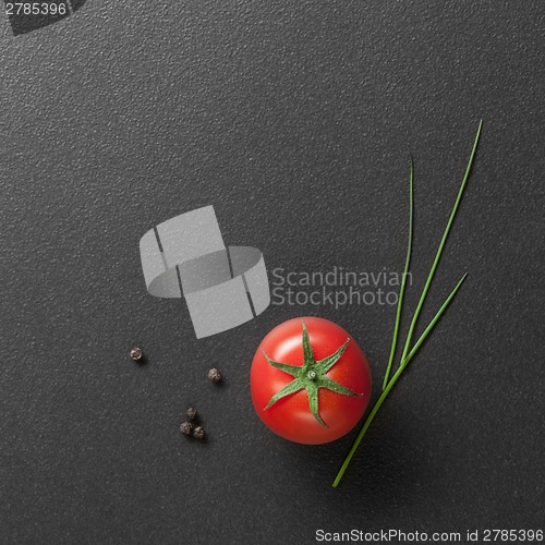 Image of red tomato with green onion on black