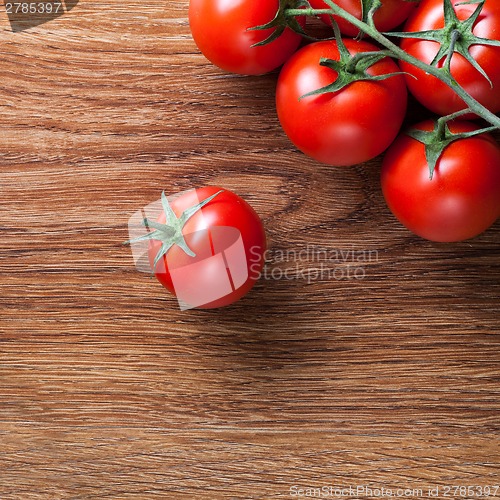 Image of red tomatoes with green salad on wood