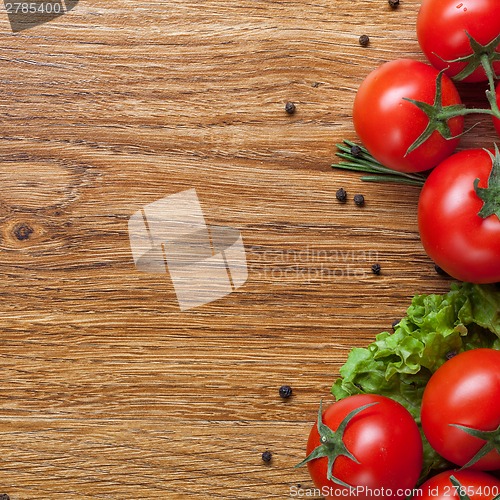 Image of red tomatoes with green salad on wood