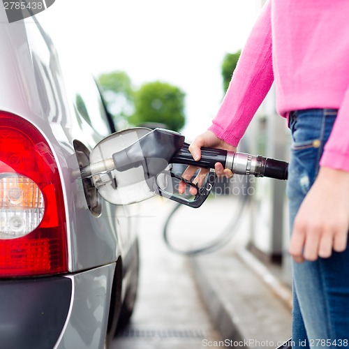 Image of Lady pumping gasoline fuel in car at gas station.