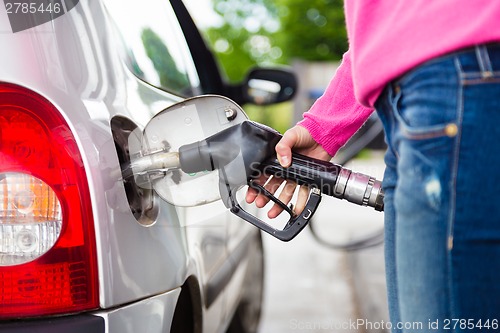 Image of Lady pumping gasoline fuel in car at gas station.