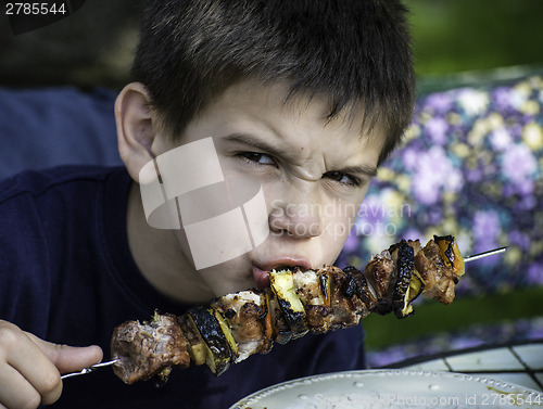 Image of Child eating meat on a skewer