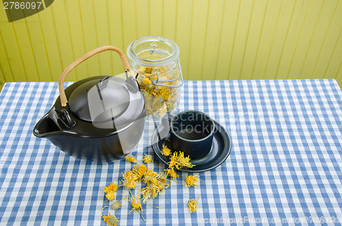 Image of dried coltsfoot herbal on table and clay tea set 