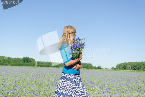 Image of girl with bluet bouquet in wide meadow back view  