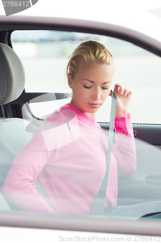 Image of Beautiful woman fastening seat belt.