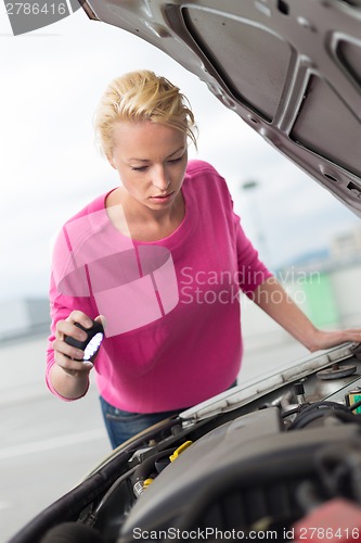 Image of Woman inspecting broken car engine.
