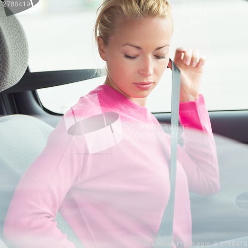 Image of Beautiful woman fastening seat belt.