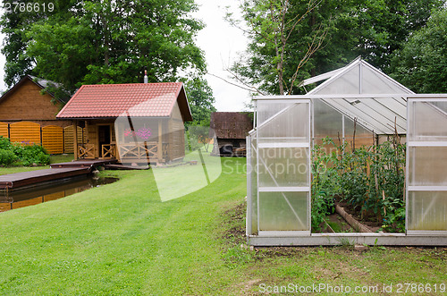 Image of greenhouse and traditional wooden bath in village  